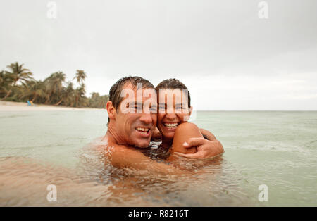 Portrait d'un couple hugging tout en nageant dans l'océan. Banque D'Images