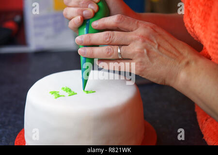 Close up of hands Décorer un gâteau de Noël avec glaçage vert Banque D'Images