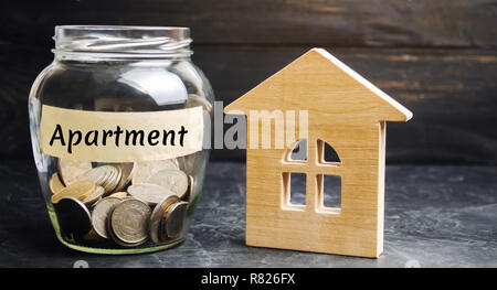 Un bocal de verre avec des pièces de monnaie et une maison en bois et l'inscription 'vacances'. L'accumulation de l'argent pour acheter un appartement. Louer un appartement, maison. R Banque D'Images