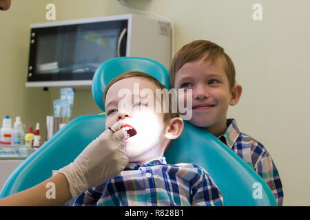Réception à l'art dentaire. Un petit garçon est sur la table et son frère reste derrière Banque D'Images