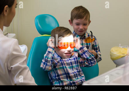Réception à l'art dentaire. Un petit garçon se pose sur le canapé et la tenue d'une des lunettes Banque D'Images