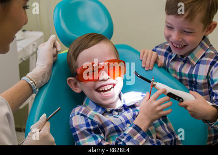 Réception à l'art dentaire. A smiling little boy jette sur la table et son frère d'un séjour près de lui Banque D'Images