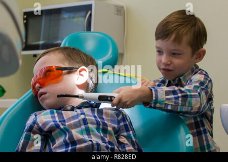Réception à l'art dentaire. Deux garçons dans l'armoire. Un petit garçon est sur la table et son frère qui maintiennent la lampe Banque D'Images