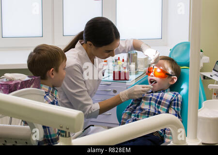 Réception à l'art dentaire. Deux garçons dans l'armoire. Un petit garçon est sur la table et son frère en le regardant. Banque D'Images