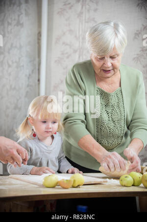 Une vieille femme faisant peu de tartes avec sa petite-fille. Pétrir la pâte Banque D'Images