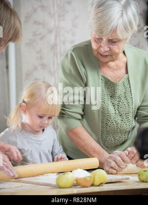 Une vieille femme faisant peu de tartes avec sa petite-fille. Rouler la pâte Banque D'Images