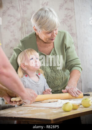 Une vieille femme faisant peu de tartes avec sa petite-fille. La farine sur les lèvres de fille Banque D'Images