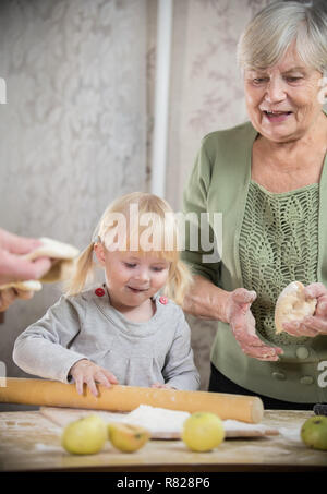 Une vieille femme faisant peu de tartes avec sa petite-fille. La fille sort de rouler la pâte Banque D'Images