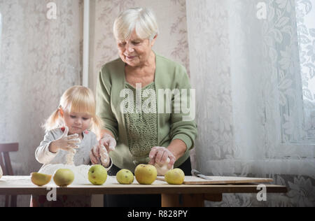 Bénéficiant d'une vieille femme faisant peu de tartes aux pommes avec sa petite-fille. Banque D'Images