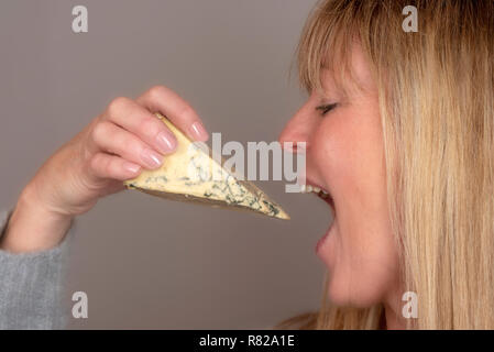 Blonde woman eating et bénéficiant d'une cale de fromage bleu Banque D'Images