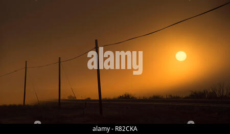 Lever du soleil à travers la brume et la poussière de Alpine, l'ouest du Texas. Banque D'Images