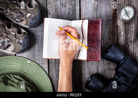 Homme écrit dans l'ordinateur portable sur la table en bois avec traveler outfit Banque D'Images