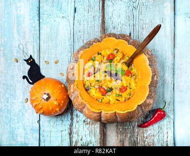 Avec la soupe de lentille dans la citrouille sculptée et black cat jouet sur le fond en bois bleu à Halloween party Banque D'Images