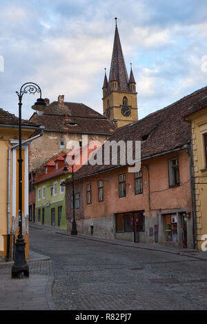 Pavés de rue typique ville de Sibiu en Roumanie, aux maisons colorées, clocher de l'église et lampadaire Banque D'Images