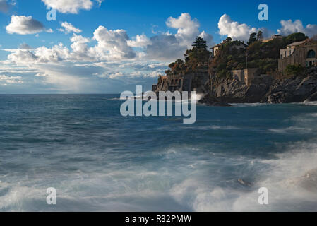 Des falaises rocheuses et de surf le long de la côte à Bogliasco sur la Riviera italienne sous un nuage ciel bleu Banque D'Images