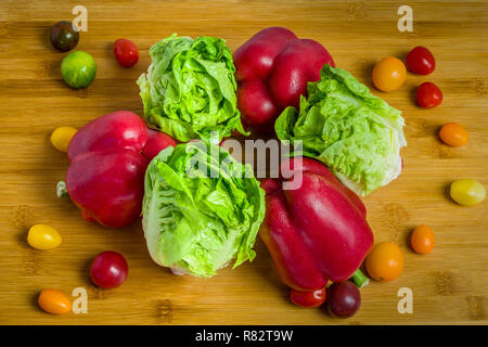 Salade verte fraîche, poivrons rouges et tomates cerises sur fond de bois Banque D'Images