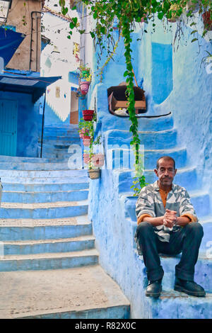 Chefchaouen, Maroc - 31 octobre 2016 : l'homme assis à la porte de sa maison dans une belle rue de Chefchaouen, Maroc Banque D'Images