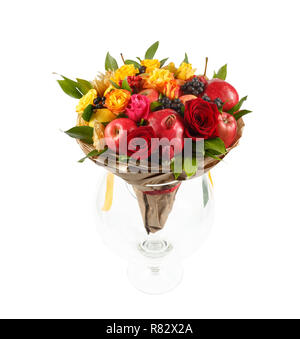 Cadeau original sous la forme d'un bouquet composé de roses rouges et jaunes, grenades, pommes, citron, poires enveloppé dans du papier kraft, debout dans une lar Banque D'Images