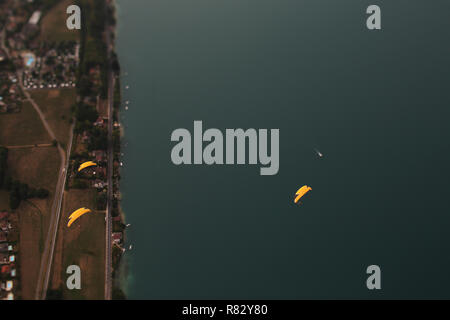 Plusieurs pilotes de tandem et de leurs passagers respectifs en survolant le Lac d'Annecy, France, en fin d'après-midi, après le coucher du soleil. Banque D'Images