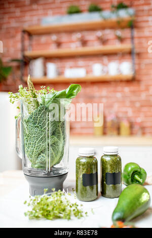 Blender smoothie plein d'ingrédients pour faire sur la table avec des légumes verts sur la cuisine Banque D'Images