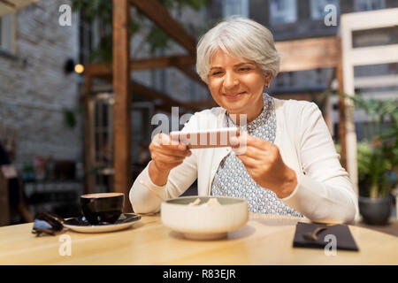 Senior woman photographing food at street cafe Banque D'Images