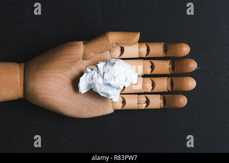 Vue de dessus du papier froissé blanc balle sur main en bois avec fond noir, pensez concept différent Banque D'Images