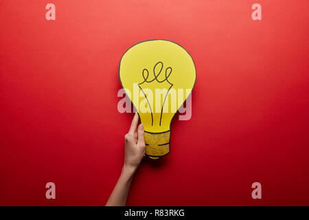 Vue de dessus de l'ampoule jaune en papier idée symbole sur fond rouge Banque D'Images