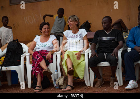 Le Mali, l'Afrique. Les femmes de race blanche blanc et noir africain aux personnes bénéficiant d'un match de football dans un village rural près de Bamako. Banque D'Images