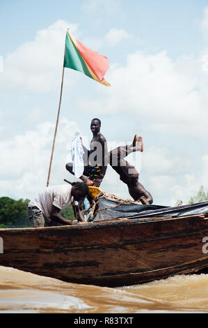 Le Mali, l'Afrique. Les jeunes hommes noirs sur l'heureux de pêche bateaux marchands de bois sur le fleuve Niger sales. Mali drapeau sur le bateau Banque D'Images