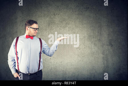 L'homme grassouillet adultes en tenue officielle et verres holding palm haut de faire présentation sur fond gris Banque D'Images