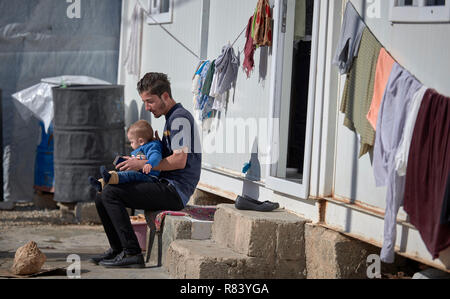 Yazidis, un homme est assis avec son enfant dans un camp de déplacés à Dawodiya dans le région du Kurdistan. Banque D'Images