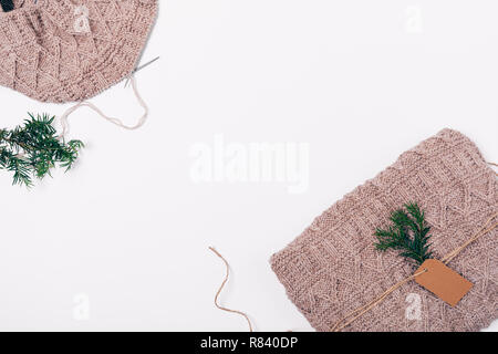 Mise à plat fait main laine tricot trame paniers comme cadeau de Noël près de branche d'arbre, vue du dessus sur fond blanc avec l'espace vide dans la zone centrale. Banque D'Images