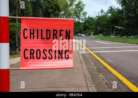 Drapeau enfants traversant le long d'une route dans une zone scolaire, à Darwin, en Australie. Banque D'Images