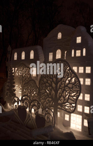 Maquettes de maisons et arbres décoratifs recouverts de neige en hiver sur parc nuit Banque D'Images