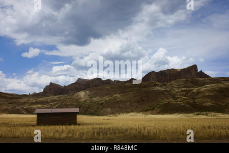 Petite cabane au milieu de la prairie, il est entouré par les montagnes Rocheuses par un beau matin d'été dans la région de Cody, Wyoming, USA. Banque D'Images