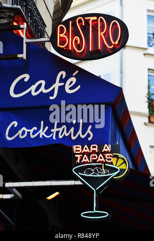 Auvent de café parisien en bleu avec un panneau néon rouge lumineux „Bistro“ et un panneau néon en forme de verre à cocktail „Bar à Tapas“ en dessous – Montmartre – Paris – France Banque D'Images