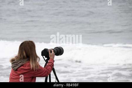 Femme photographe utilisant téléobjectif à la compétition de surf Banque D'Images