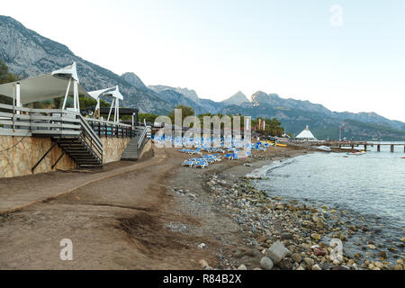 Mer plage déserte avec transats vides au coucher du soleil de la journée sur fond de hautes montagnes rocheuses en Turquie Banque D'Images