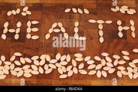 Mot "santé" énoncés de pompage sec seeds sur une planche à découper en bois. Aberdeen, Écosse, Royaume-Uni. Banque D'Images