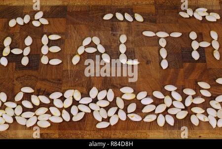 Mot "santé" énoncés de pompage sec seeds sur une planche à découper en bois. Aberdeen, Écosse, Royaume-Uni. Banque D'Images