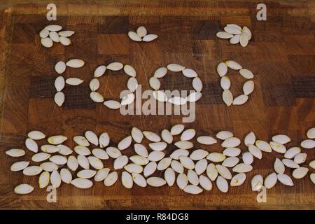 Mot "nourriture" énoncés de pompage sec seeds sur une planche à découper en bois. Aberdeen, Écosse, Royaume-Uni. Banque D'Images