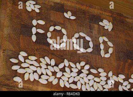 Mot "nourriture" énoncés de pompage sec seeds sur une planche à découper en bois. Aberdeen, Écosse, Royaume-Uni. Banque D'Images