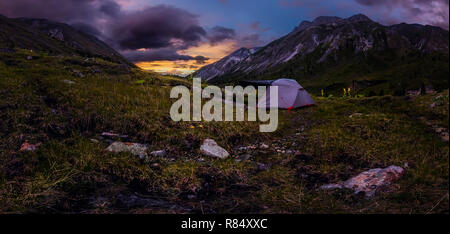 Panorama tente dans la montagne sur un fond de nuages pourpres au coucher du soleil. Banque D'Images