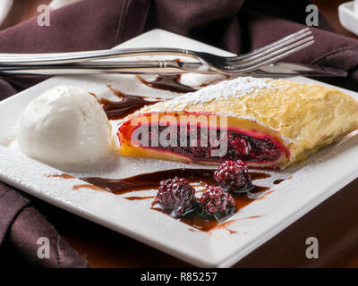 Strudel aux pommes - dessert sucré avec cherry et blackberry sur plaque blanche avec ice cream au restaurant table Banque D'Images