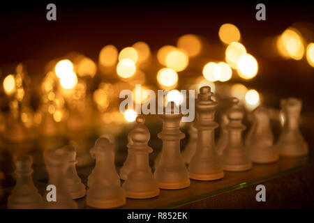 Gros plan d'une série d'échecs en verre avec des lumières dans l'arrière-plan Banque D'Images