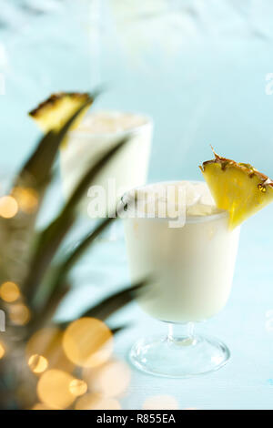 Pina Colada servi avec des tranches d'ananas. Les feuilles d'ananas avec lumières de fête en effet bokeh, fond bleu, une haute résolution Banque D'Images