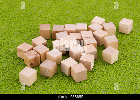 Cubes en bois sur fond de plastique vert. Banque D'Images