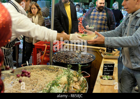 Un chef italien autre qu'un client un carton alimentaire avec de l'épeautre risotto aux champignons sauvages, chaud la cuisson à Borough Market stall London England UK KATHY DEWITT Banque D'Images