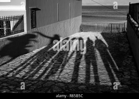 Les ombres de l'après-midi longue de sept personnes debout en face d'une plate-forme d'observation à Corfou, l'île de Kerkira, Grèce et la mer derrière la f métallique Banque D'Images