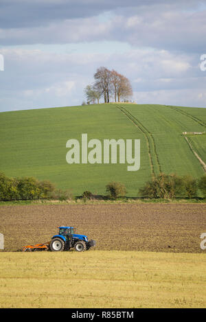 Un tracteur cultive le champ ci-dessous Brightwell Barrow, un bol de l'âge du Bronze Barrow sur la colline à côté de Little Wittenham, Oxfordshire. Banque D'Images